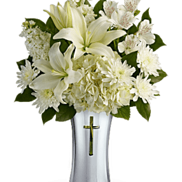 White lilies and chrysanthemums in a white vase with a cross