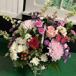 Mixed bouquet of pink, white, and purple flowers in a white container