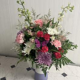 Mixed bouquet in a lavender vase with pink, white, and purple flowers