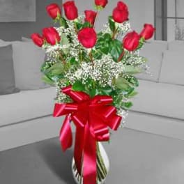Red roses in a white vase with a large red ribbon
