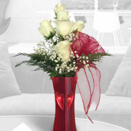 White roses in a red vase with a sheer red ribbon
