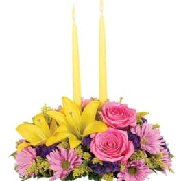 Pink roses and daisies arranged with two yellow taper candles