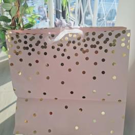 Pink gift bag with gold polka dots and white ribbon handles