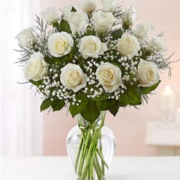 White roses arranged in a clear glass vase with baby's breath