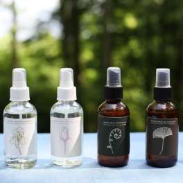 Four botanical spray bottles on a table outdoors