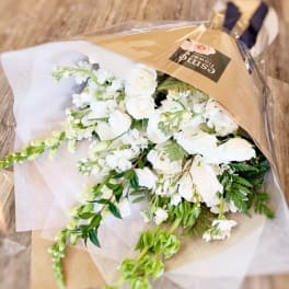 White flower bouquet wrapped in brown paper and clear plastic