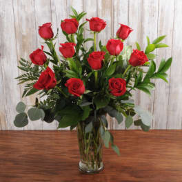 Tall bouquet of long-stemmed red roses arranged in a clear glass vase