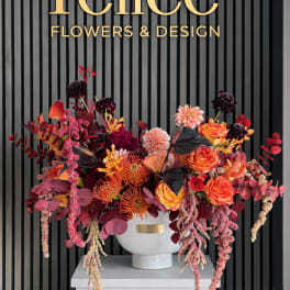 Large colorful floral arrangement in a white vase beneath a Felice Flowers & Design sign