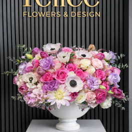 Large pink and lavender flower arrangement in a white pedestal vase