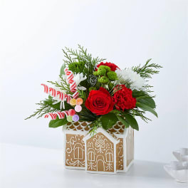 Christmas floral arrangement in a gingerbread house container with candy canes