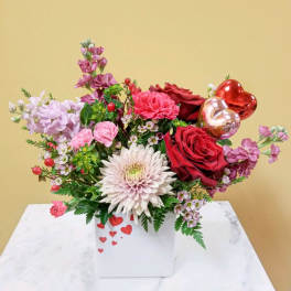 Mixed bouquet with red roses, pink blooms, and heart balloons in a white box