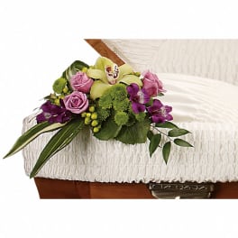 Floral spray with pink roses, orchids, and green mums on a casket