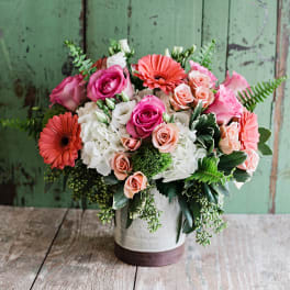 Mixed pink, peach, and white flowers arranged in a white vase