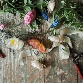 Loose flowers and greenery laid on a rustic wooden surface with pruning tools