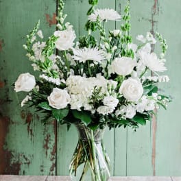 White roses and daisies arranged in a clear glass vase