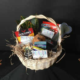 Gift basket with dog treats, toys, and a plush dog in a wicker basket