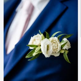 White rose boutonniere pinned to a blue suit jacket