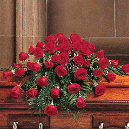 Red rose casket spray arranged across a wooden casket