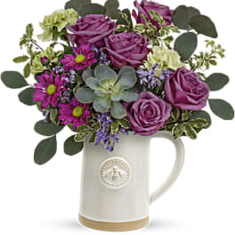 Purple roses and daisies arranged in a white ceramic mug