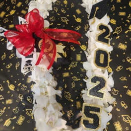 White floral graduation lei with 2025 numbers and a red bow on a black celebratory background