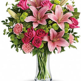 Tall glass vase of pink lilies, roses, and carnations with green button mums
