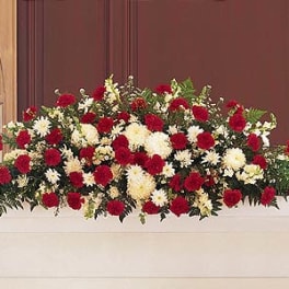 Red and white funeral casket spray of carnations and mums in a long, low design