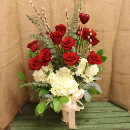 Red roses and white hydrangeas in a tall arrangement with a ribbon bow