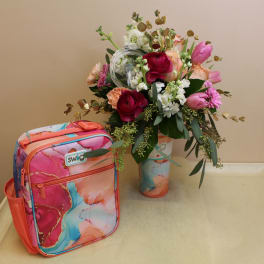 Mixed bouquet in a painted vase beside a colorful lunch bag