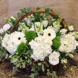 White flowers arranged in a wicker basket with green accents