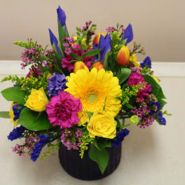 Bright mixed bouquet in a black vase with yellow, pink, and blue flowers