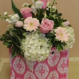 Pink roses and pale gerbera daisies in a patterned gift bag