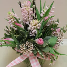 Pink tulips and pale hyacinths in a glass vase with a pink ribbon