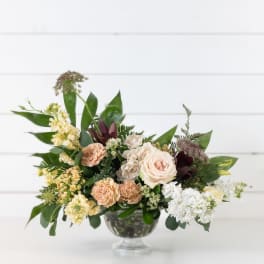 Mixed bouquet of pale roses and carnations in a clear glass vase