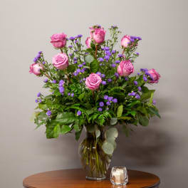 Pink roses and purple filler flowers in a glass vase