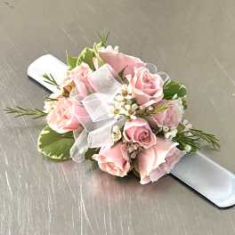 Pink rose wrist corsage with white ribbon on a satin band