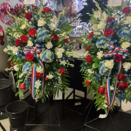 Two large standing floral sprays with red, white, and blue flowers