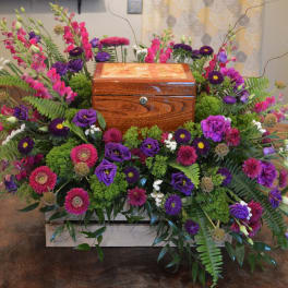 Colorful floral arrangement surrounding a wooden urn box