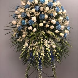 Large standing floral spray with white roses, blue carnations, and orchids