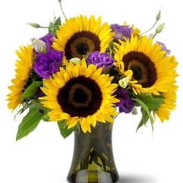Sunflowers and purple blooms arranged in a dark glass vase
