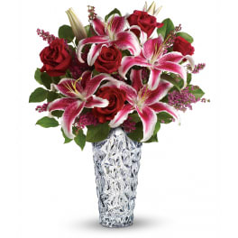 Red roses and pink lilies arranged in a clear textured vase
