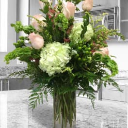 Tall bouquet of pale pink roses and white hydrangea in a glass vase