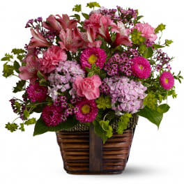 Pink and purple mixed flower arrangement in a wooden basket