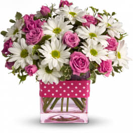 Pink roses and white daisies in a pink glass vase with a polka-dot ribbon