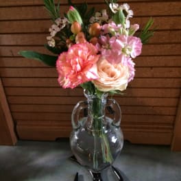 Pink and peach flowers arranged in a clear glass vase