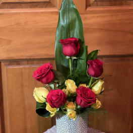 Tall arrangement of red and yellow roses in a patterned vase