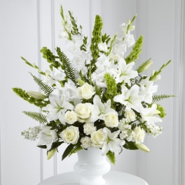 White floral arrangement in a white vase with roses and lilies