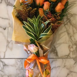 Bouquet of orange roses wrapped in clear plastic with an orange ribbon