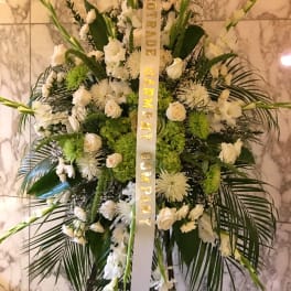 Large white funeral spray with a condolence ribbon