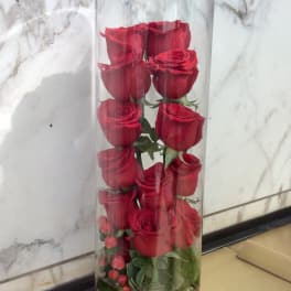 Tall glass cylinder with red roses and pebbles