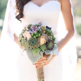 Bride holding a succulent bouquet with pale roses